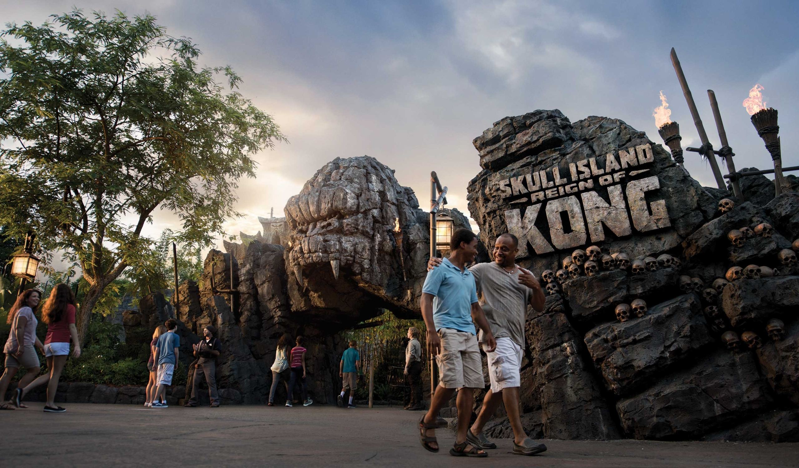 A father an his teenage sun outside the ride sign for the Skull Island, Reign of Kong ride