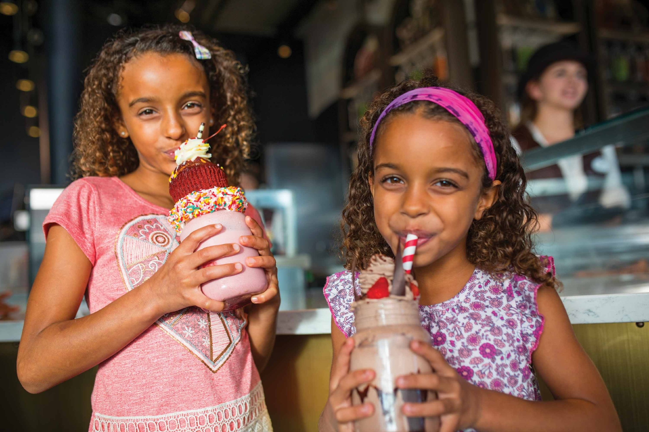 Two children enjoying extravagant milkshakes