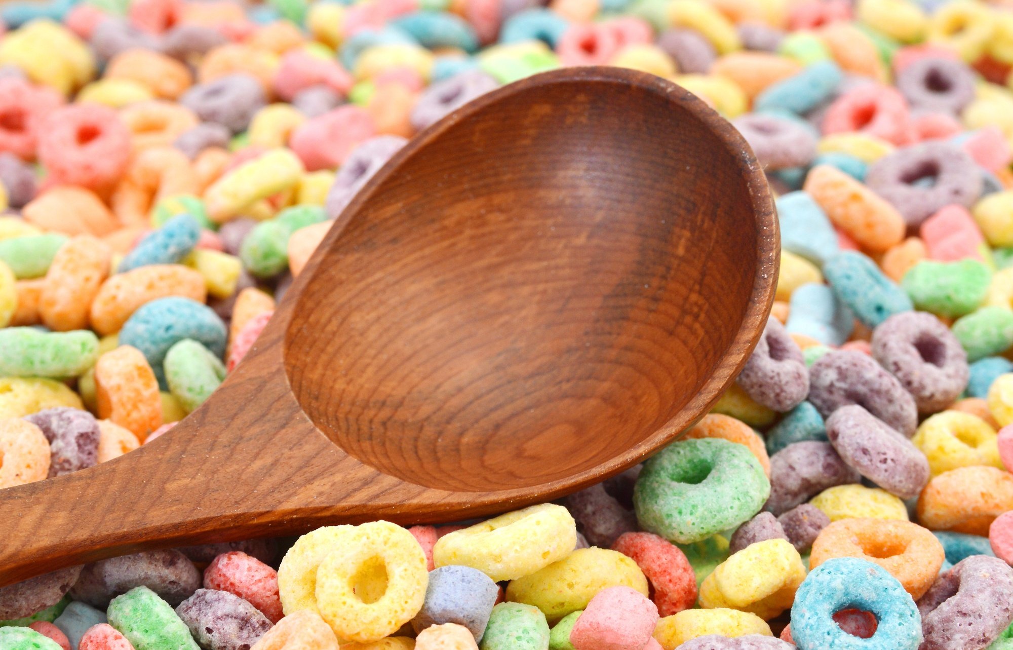 A wooden spoon surrounded by colorful breakfast cereal