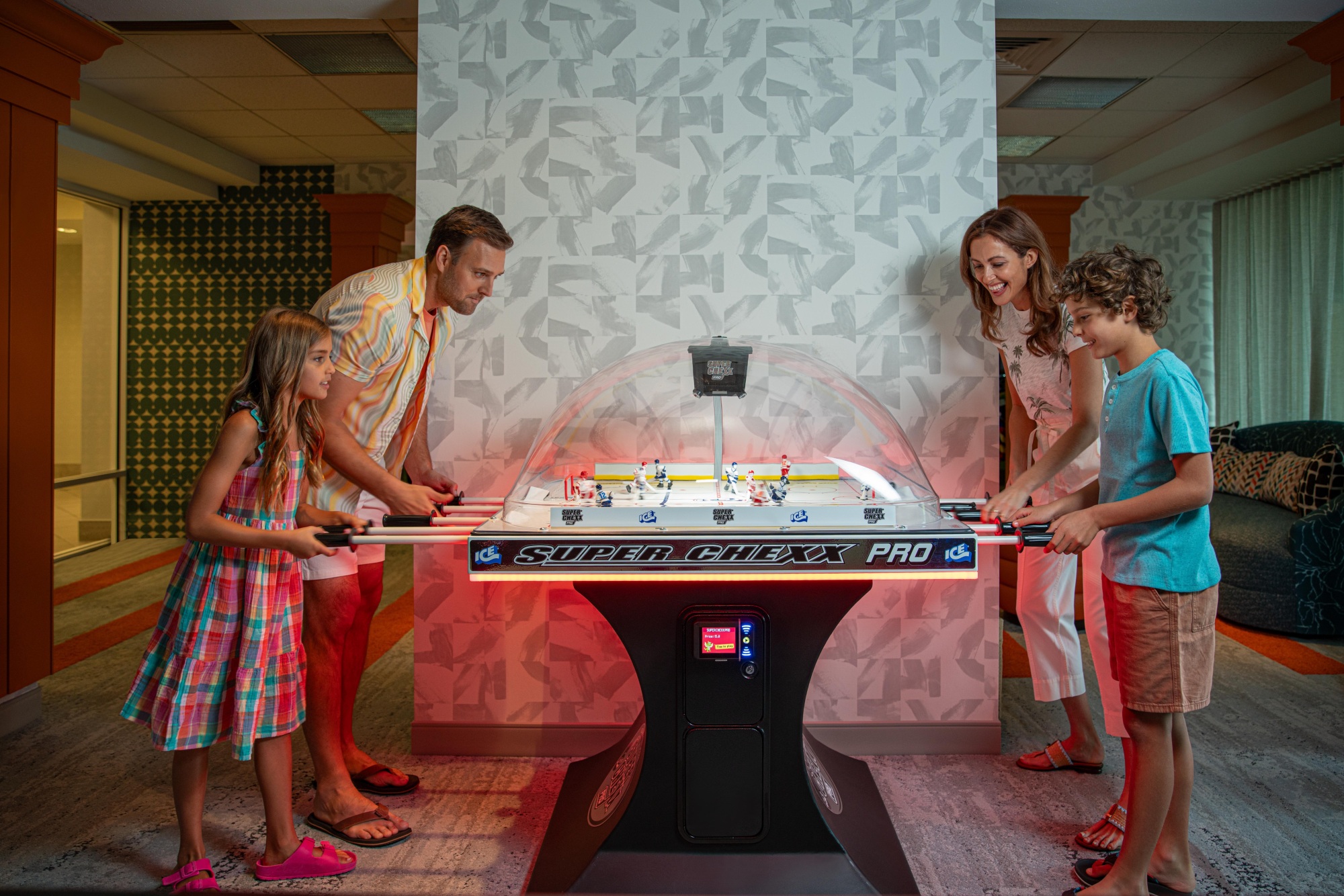 A family plays table hockey at Kinetic, the arcade at Hotel Landy.