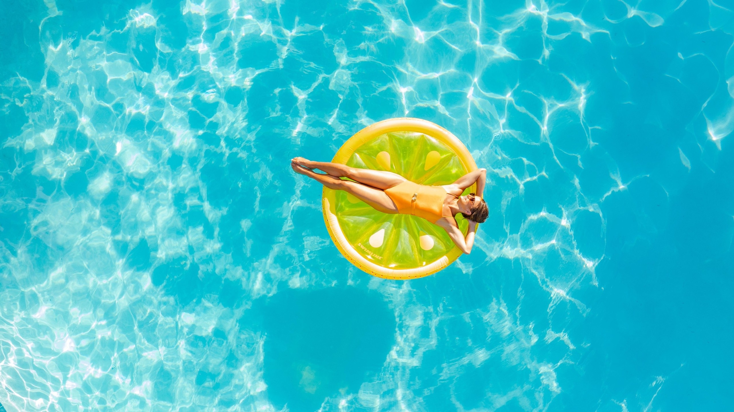 woman floating in a pool on a flotation device shaped like a lemon